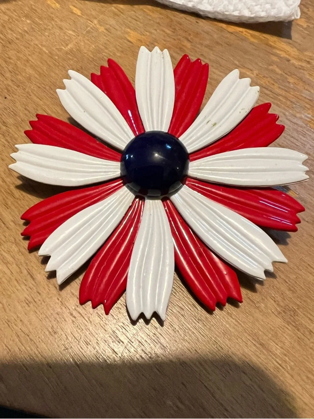 1960s enamel brooch with red and white petals and blue dome center.